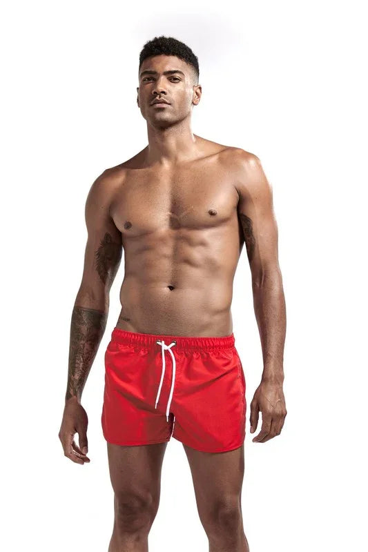 Man wearing red short swim shorts with drawstring from Good Trouble Garments by Good Trouble Fashion