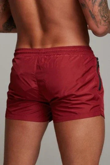 Good Trouble Garments short sexy swim trunks in red with zipper pocket detail on male model