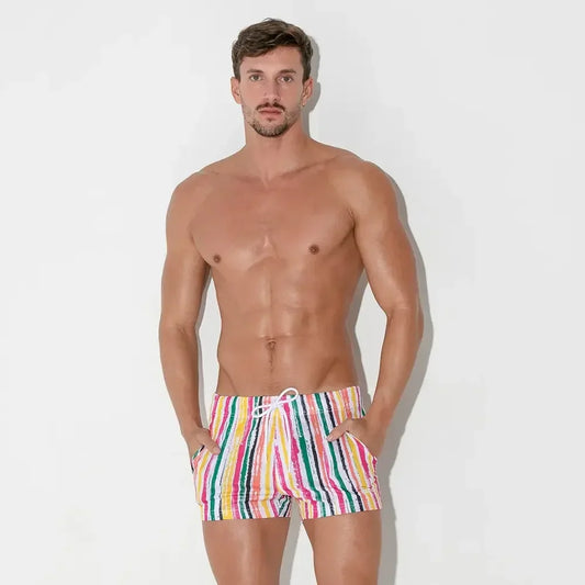 Male model wearing colorful striped swim shorts from CODE 22 branded swimwear collection
