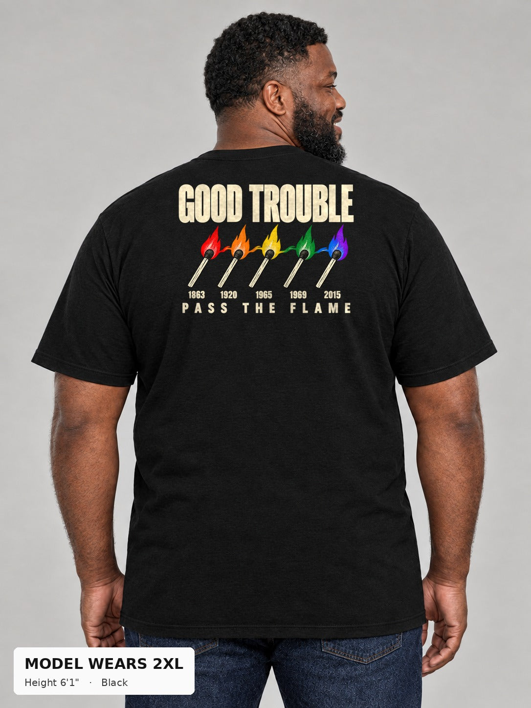 Good Trouble Pass the Flame Tee in Black, back view showing the PASS THE FLAME five-match back print, on a plus-size model wearing size 2XL, 6'1" - Good Trouble Fashion