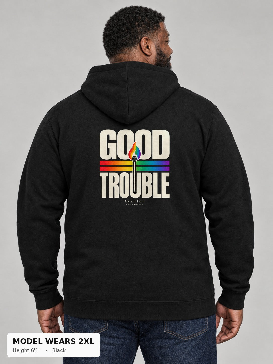 Good Trouble Spark Hoodie in Black, back view showing the GOOD TROUBLE rainbow match back print, on a plus-size model wearing size 2XL, 6'1" - Good Trouble Fashion