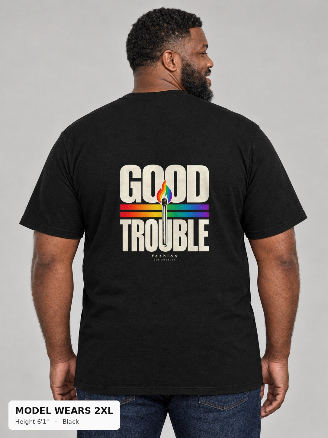 Good Trouble Spark Tee in Black, back view showing the GOOD TROUBLE rainbow match back print, on a plus-size model wearing size 2XL, 6'1" - Good Trouble Fashion